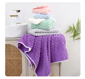 Detalle de toalla de baño forro polar coral a cuadros, textura suave y absorbente.