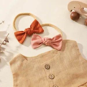 High-detail shot of soft baby bow headbands and organic linen vest with wooden buttons