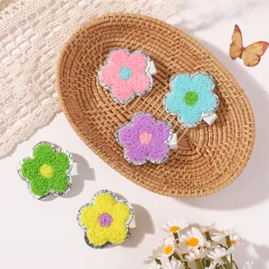 Detailed close-up of colorful chenille flower hair clips with sparkling glitter borders