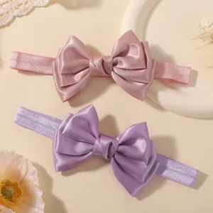Détail montrant le satin lisse et l'élégant nœud à double épaisseur sur les bandeaux bébé