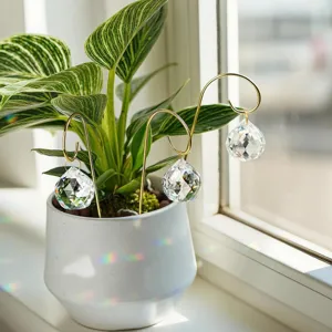 Detailansicht von facettierten Kristallkugel-Sonnenfängern an goldenen Stäben im Topf.