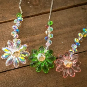 Vue détaillée d'attrape-soleil en fleur de cristal irisé, vert et rose sur fond en bois
