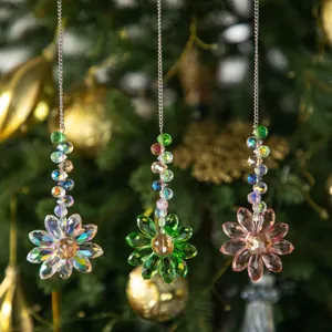 Gros plan de trois attrape-soleil en fleur de cristal suspendus à un sapin de Noël