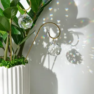 Nahaufnahme eines Kristallprisma-Lichtfängers an einem goldenen Gitter im Blumentopf