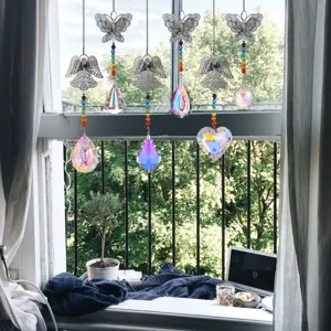 Prismi di cristallo acchiappasole con pendenti a farfalla e angelo su una finestra soleggiata.