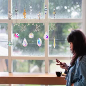 Crystal suncatchers with butterfly pendants hanging by a rainy window in a cozy room