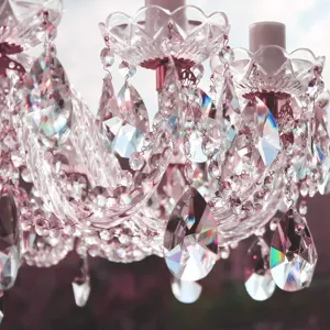 Nahaufnahme von rosa facettierten Kristallleuchter-Anhängern mit Regenbogen-Reflexion.