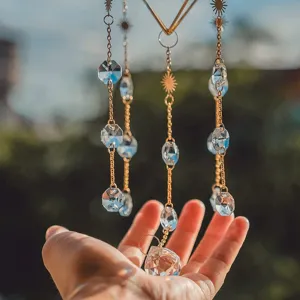 Detailed close-up of a hanging crystal suncatcher held by a hand in natural sunlight