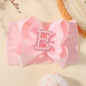 Bandeau bébé rose avec grand nœud et détail lettre E en perles et strass brillant