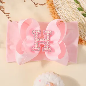 Bandeau bébé rose avec gros nœud et lettre H ornée de perles élégante