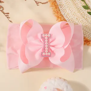 Adorable bandeau bébé rose avec grand nœud et lettre I ornée de perles et de strass fins