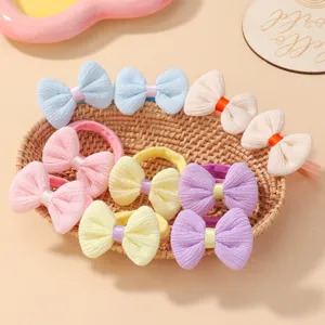 Vue détaillée de chouchous à nœuds tricotés colorés pour filles dans un panier tressé.