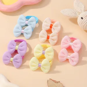 Vue détaillée de chouchous à nœuds tricotés colorés pour filles sur fond beige doux