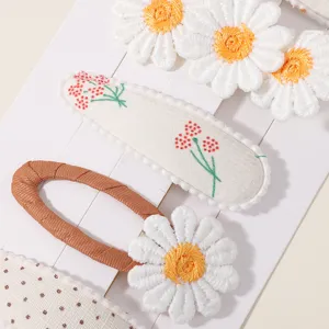 Detailaufnahme mit bestickten Gänseblümchen-Motiven auf BB-Haarspangen aus Stoff