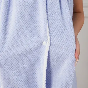 Waffle texture bath towel wrap detail showing soft fabric, white piping and snap button.