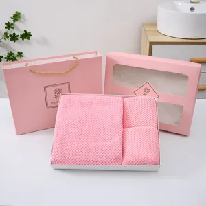 Detalle de set de regalo de toallas de baño de vellón de coral rosa con textura suave y caja elegante.