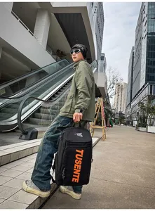 Ein Modell im urbanen Streetstyle trägt einen großen schwarzen Sportrucksack mit oranger Schrift