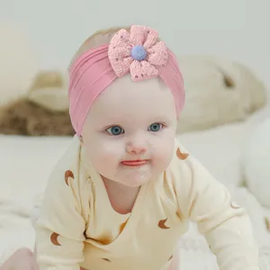 Cute baby girl wearing a pink floral wide headband with a blue center flower detail