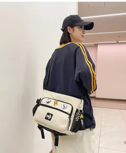 Casual cream canvas messenger bag with stylish badges for students and commuting