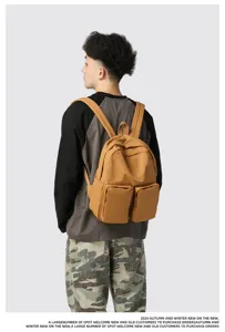 Back view of model wearing a stylish brown canvas backpack with double front pockets