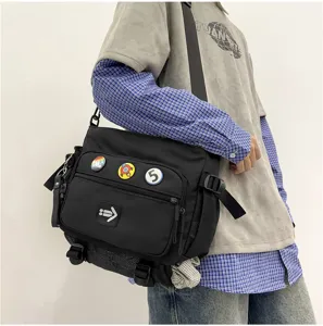 Side view of a black large capacity messenger bag with decorative badges for men and women.