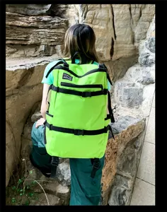 Grote neon groene wandelrugzak gedragen door een model in een ruige bergachtige omgeving