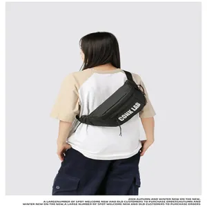 Vista trasera de modelo con el bolso de pecho negro con estampado de letras CONK LAB