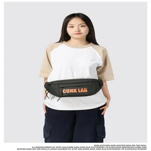 Detalle de riñonera negra de estilo urbano con letras CONK LAB naranjas en modelo
