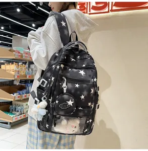 Dettaglio di un grande zaino nero per studenti con stampe di stelle e ciondoli carini.