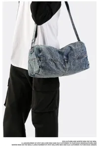 Model wearing a large distressed blue denim crossbody travel bag with acid wash finish