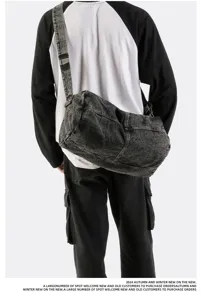 Back view of a man carrying a large trendy vintage washed denim messenger bag detail