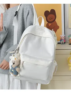 Sac à dos blanc décontracté avec un joli porte-clés ours dans un décor d'étudiant