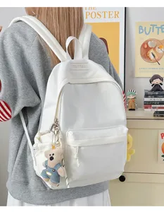 Vue arrière d'un sac à dos étudiant blanc minimaliste avec un joli pendentif d'ours