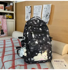 Vista dettagliata di uno zaino scolastico nero con motivo a stelle bianche e ciondoli in peluche.