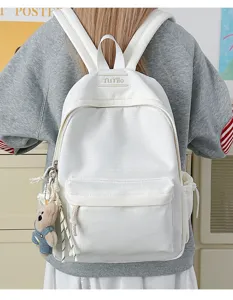 Vue arrière d'un sac à dos scolaire blanc minimaliste avec un joli pendentif d'ours