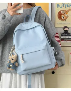 Détail d'un sac à dos scolaire bleu clair avec un adorable charm d'ours en peluche.