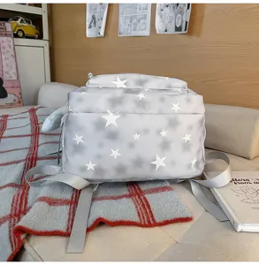 Zaino grigio per studenti con stelle bianche mostrato in un accogliente ambiente studio