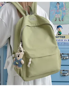 Vue détaillée d'un sac à dos d'étudiant vert clair avec pendentif ours et logo
