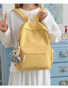 Détail d'un sac à dos d'écolier jaune avec breloque ours porté par un mannequin