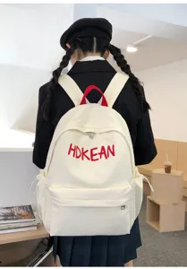 Vue arrière d'un sac à dos d'étudiant blanc avec broderie de lettres rouges sur modèle