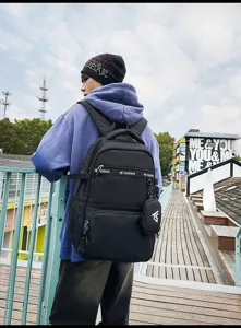 Rückansicht eines Schülers mit einem großen schwarzen Rucksack in urbaner Straßenumgebung