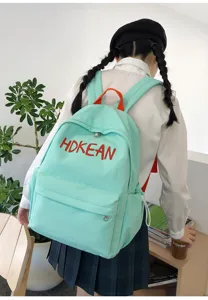 Vue détaillée d'un sac à dos d'école vert menthe avec broderie de lettres rouges sur modèle