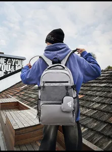 Junger Mann trägt einen grauen College-Rucksack mit praktischem Netzdetail auf einem Dach.
