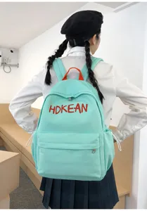 Sac à dos étudiant vert menthe avec broderie HOKEAN rouge porté par un mannequin