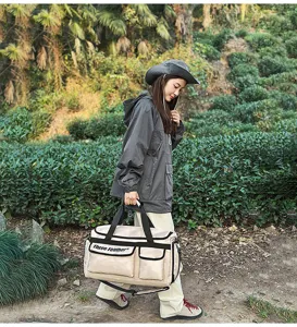 Asiatisches Model trägt eine beige Reisetasche mit großer Kapazität bei einem Parkspaziergang