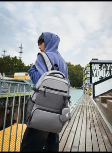 Detailansicht eines grauen großen Schülerrucksacks mit Netztasche in einer urbanen Umgebung