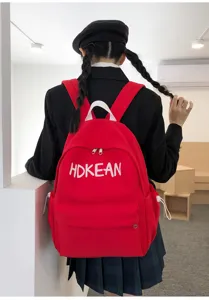 Vue détaillée d'un sac à dos d'écolier rouge léger avec broderie de lettres blanches