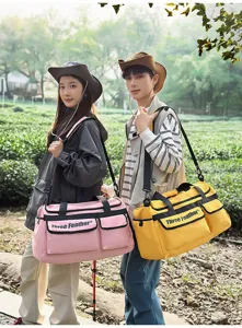 Zwei Models tragen große rosa und gelbe Outdoor-Reisetaschen in grüner Landschaft
