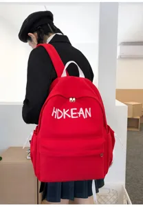 Vue arrière d'un sac à dos d'écolier rouge avec lettres brodées porté par un mannequin