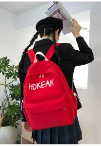 Sac à dos d'écolier rouge léger avec broderie HDKEAN porté par un mannequin dans un intérieur